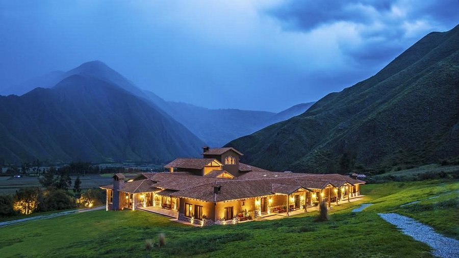 Inkaterra Hacienda Urubamba lit at dusk beneath the Sacred Valley mountains